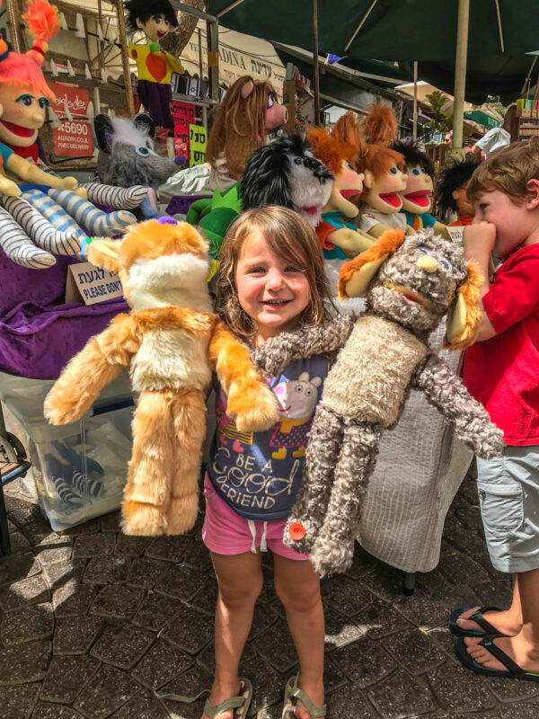 child holding puppets at Nahlat Binyamin art fair in Tel Aviv