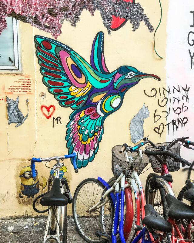 colorful painting of hummingbird (Tel Aviv street art) with bicycles parked below