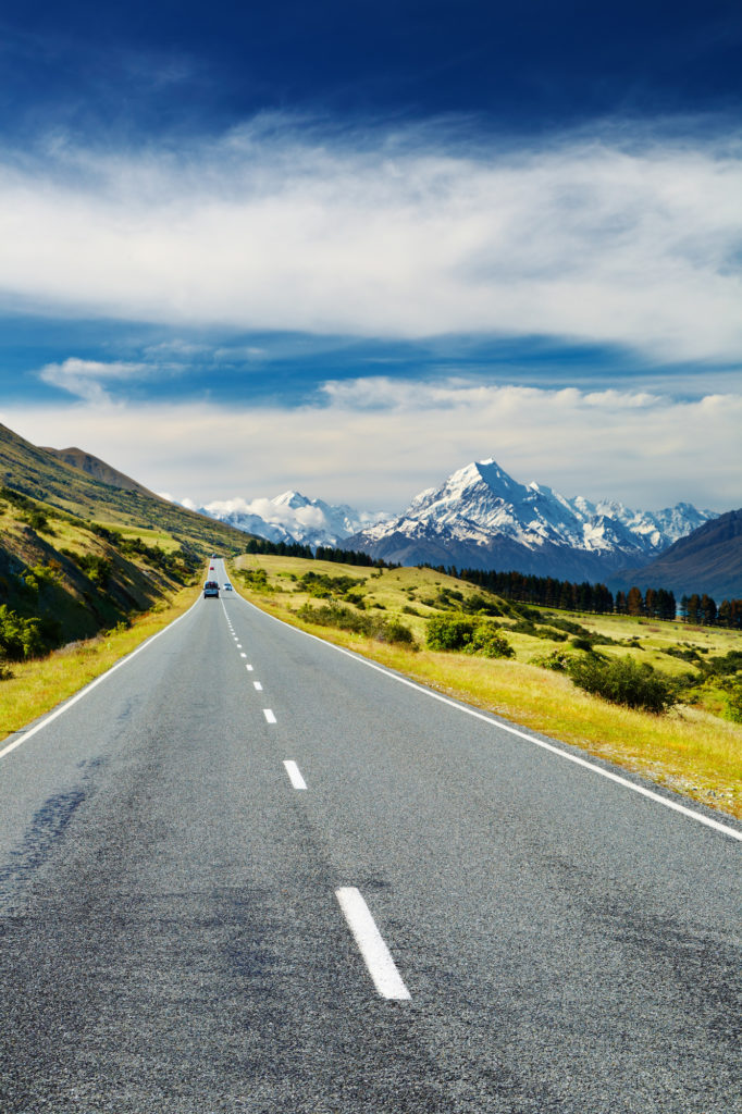 car driving on a long empty road toward Mount Cook, South Island, New Zealand