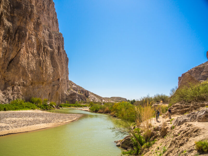 Boquillas Canyon hike in Big Bend National Park, Texas showing blue sky, green Rio Grande River and sandy canyon walls