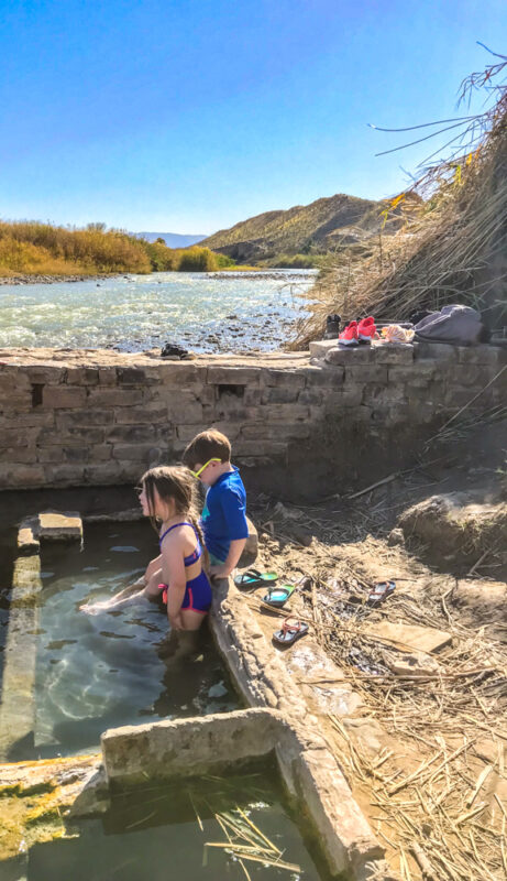 Two children sitting in the tub at Big Bend National Park hot springs along the Rio Grande River in Texas