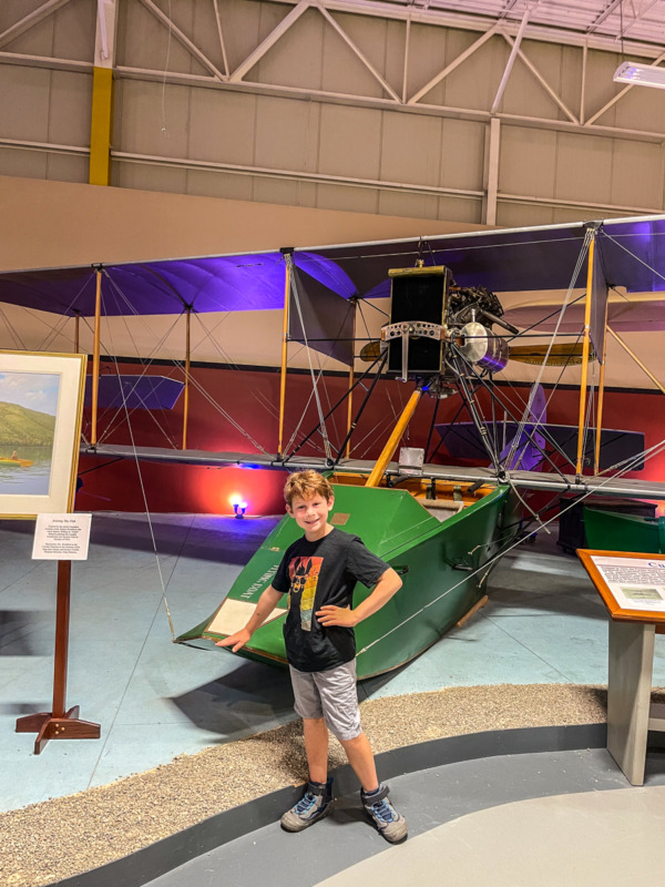 boy standing in front of amphibious plan at Glenn Curtiss Museum in Hammondsport NY - things to do in Finger Lakes with kids