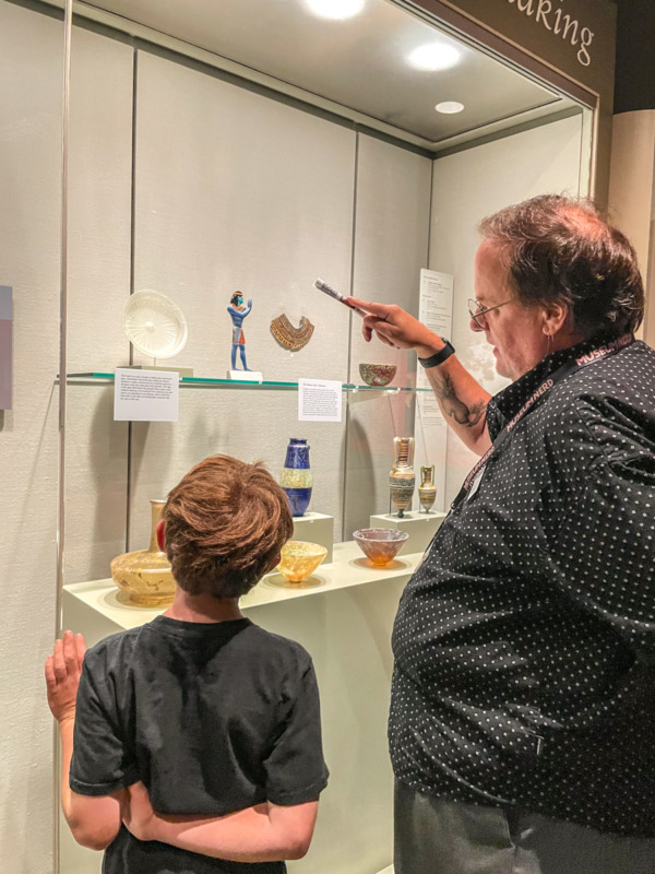 boy and tour guide looking at ancient glass at Corning Museum of Glass - things to do in Finger Lakes with kids