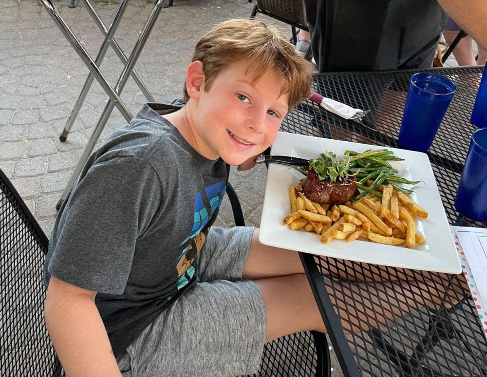 boy eating steak at Timber Stone Grill in Hammondsport NY - where to eat in Finger Lakes