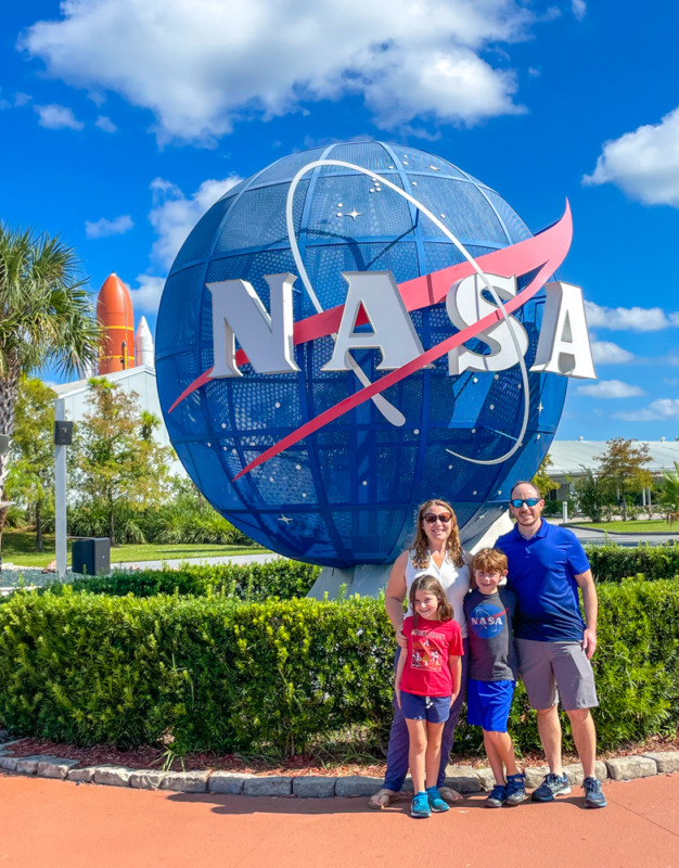 Family standing in front of NASA globe at Kennedy Space Center tour entrance